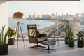 Butaca de diseño y ottoman en similpiel negra con estructura de madera, disponible en Muebles Mercatoro en Ciudad Quesada