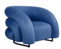 Sillón de diseño KARLOVY en terciopelo azul profundo, de líneas orgánicas y base epoxi negro, con gran confort y fuerte presencia visual.