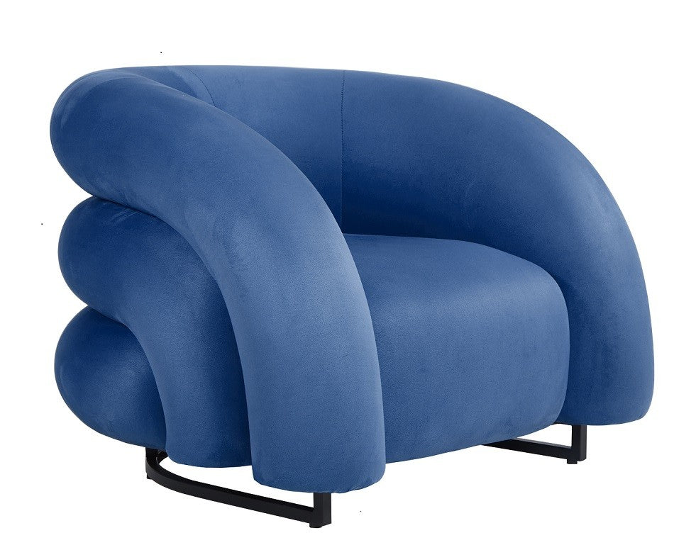 Sillón de diseño KARLOVY en terciopelo azul profundo, de líneas orgánicas y base epoxi negro, con gran confort y fuerte presencia visual.