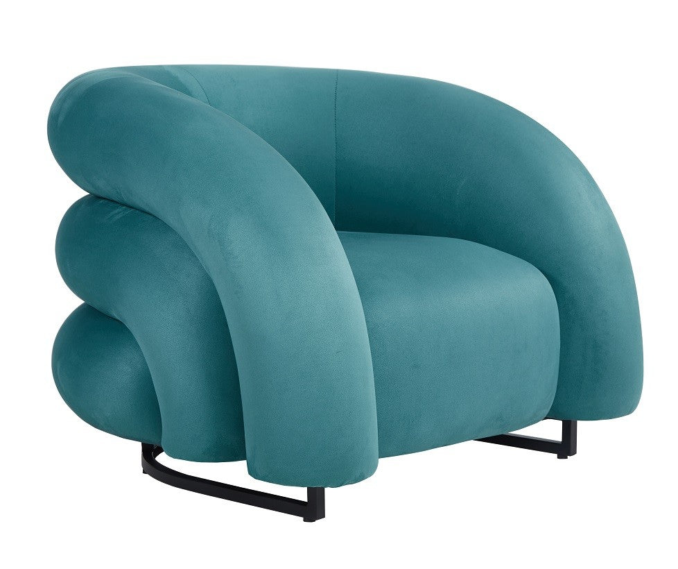 Sillón de diseño KARLOVY en terciopelo turquesa vibrante, de líneas orgánicas y acogedoras con base epoxi negro, gran confort y fuerte presencia visual mediterránea.